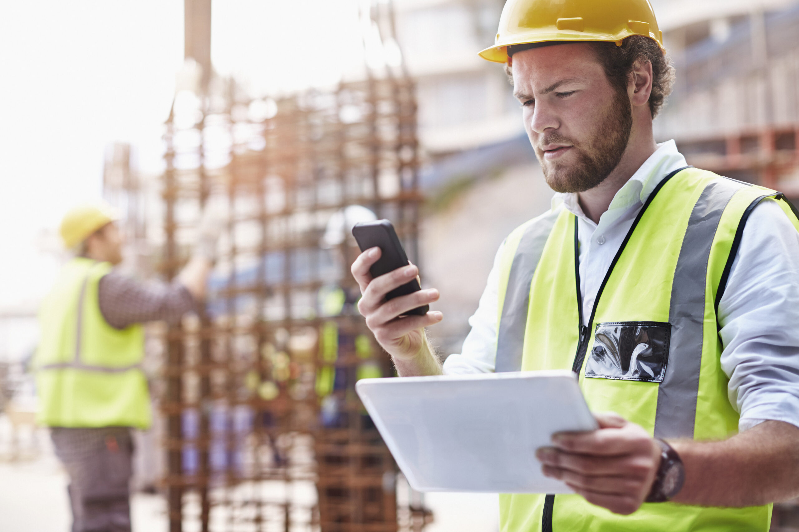 Construction worker digital tablet texting cell phone at constru